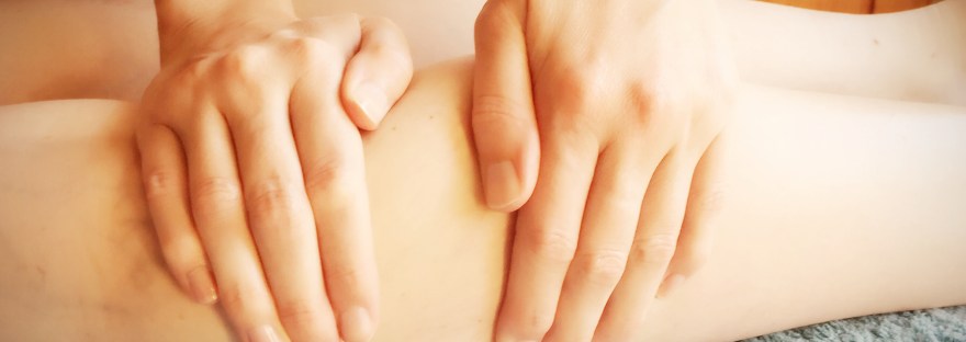 Image of two hands giving a sports massage on the legs