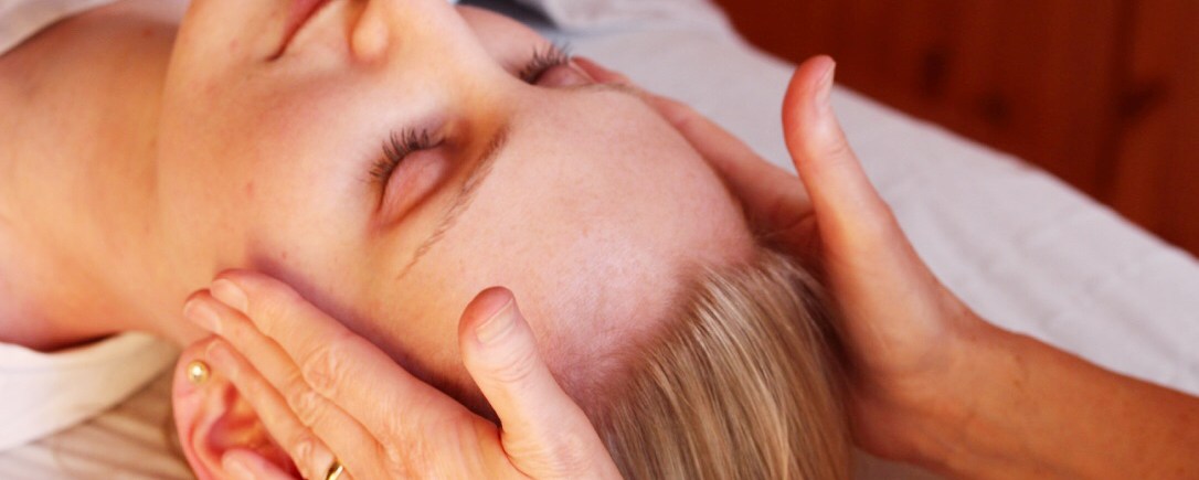 Image of a female lying down receiving osteopathy treatment to the head and neck